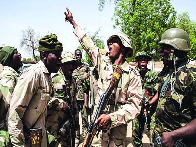 TOPSHOTS Nigerian troops celebrate after taking over Bama from Boko Haram on March 25, 2015. Nigeria's military has retaken the northeastern town of Bama from Boko Haram, but signs of mass killings carried out by Boko Haram earlier this year remain.  AFP PHOTO / NICHOLE SOBECKINichole Sobecki/AFP/Getty Images